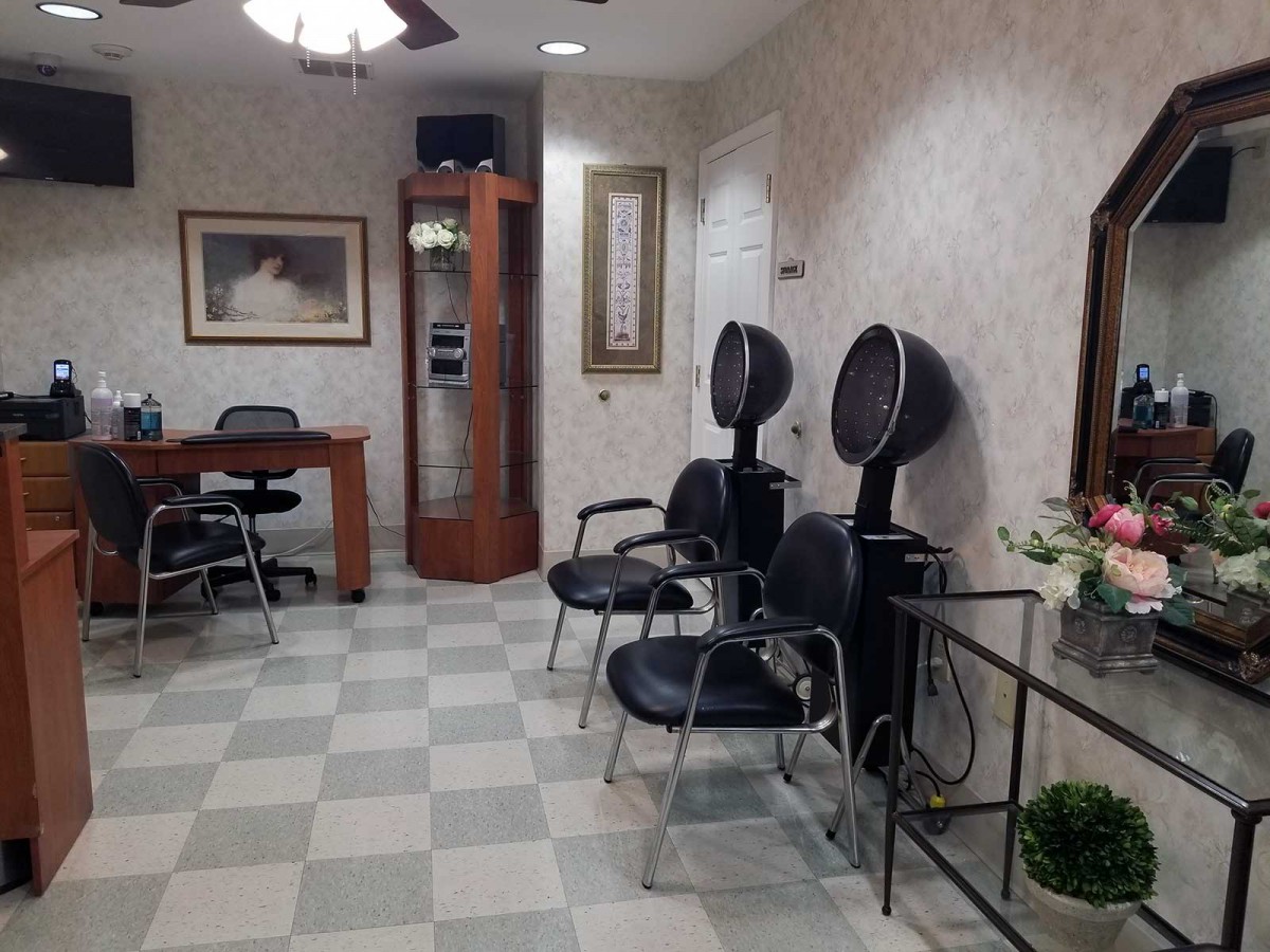 A cozy salon interior featuring chairs, hair dryers, and a desk with art on the walls.