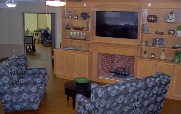 A cozy living room with a brick fireplace and wall-mounted television.