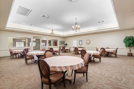 A spacious dining area featuring round tables and upholstered chairs, designed for gatherings.
