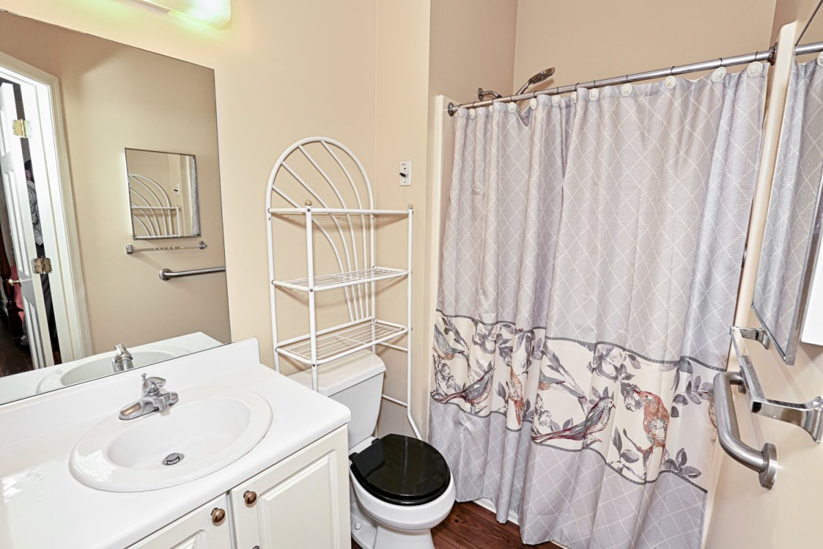 A small bathroom featuring a sink, toilet, and a shower with a decorative curtain.