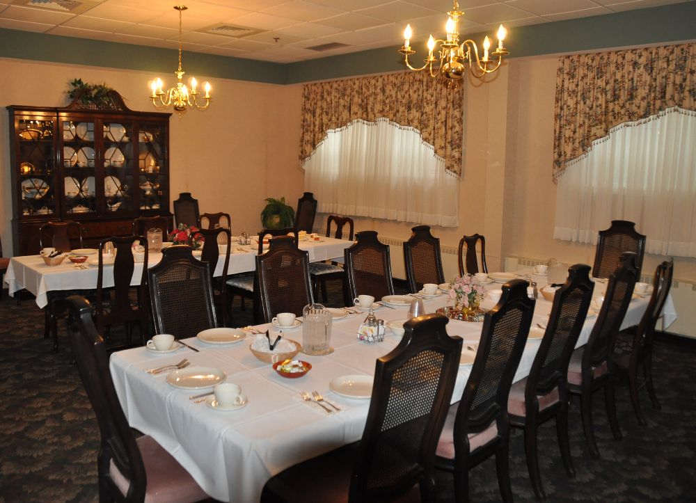 An elegant dining room with a formal table setting and chandeliers.