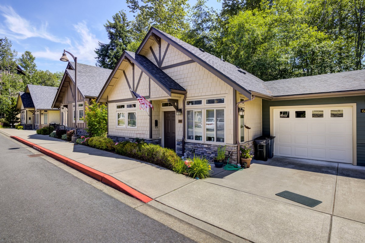 A charming cottage-style house with a garage and neatly maintained front yard.