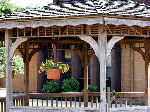 A charming gazebo featuring a hanging flower planter, surrounded by greenery.