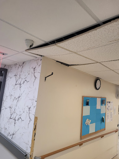 A view of a ceiling with visible damage and a wall covered in decorative elements.