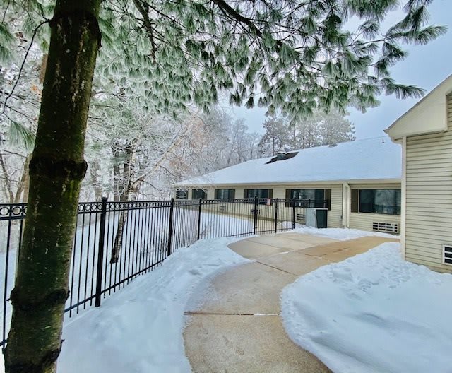 A snow-covered pathway leads to a building nestled among snowy trees.