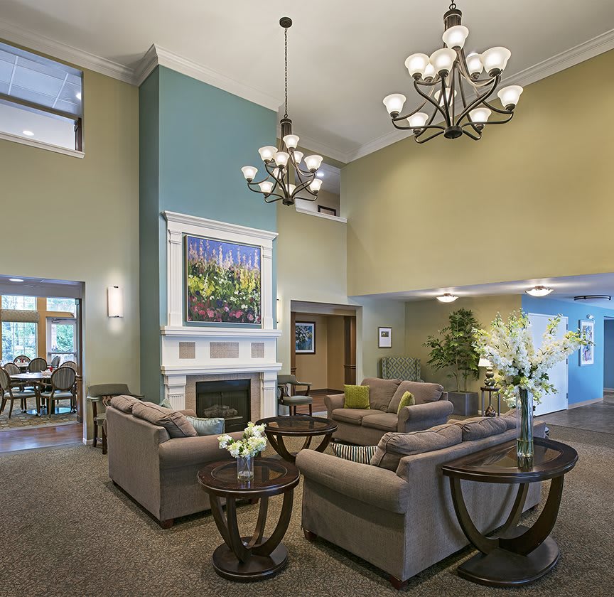 A modern living room with comfortable seating, elegant chandeliers, and a fireplace, complemented by tasteful artwork.