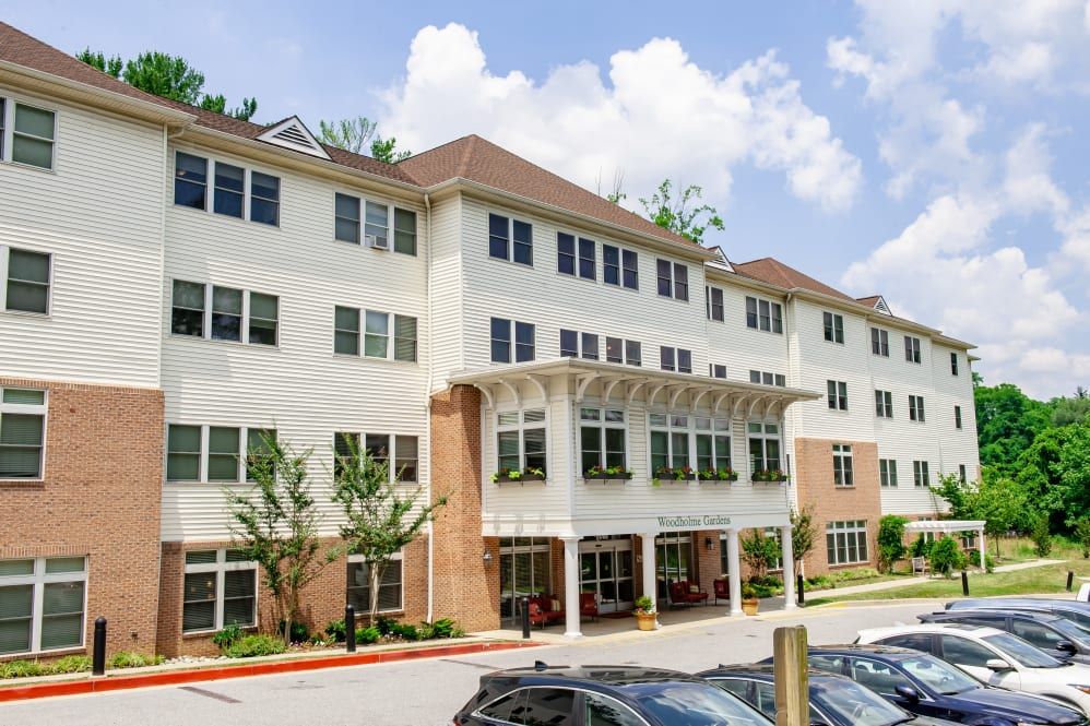 A multi-story residential building with parked cars and trees in the foreground.