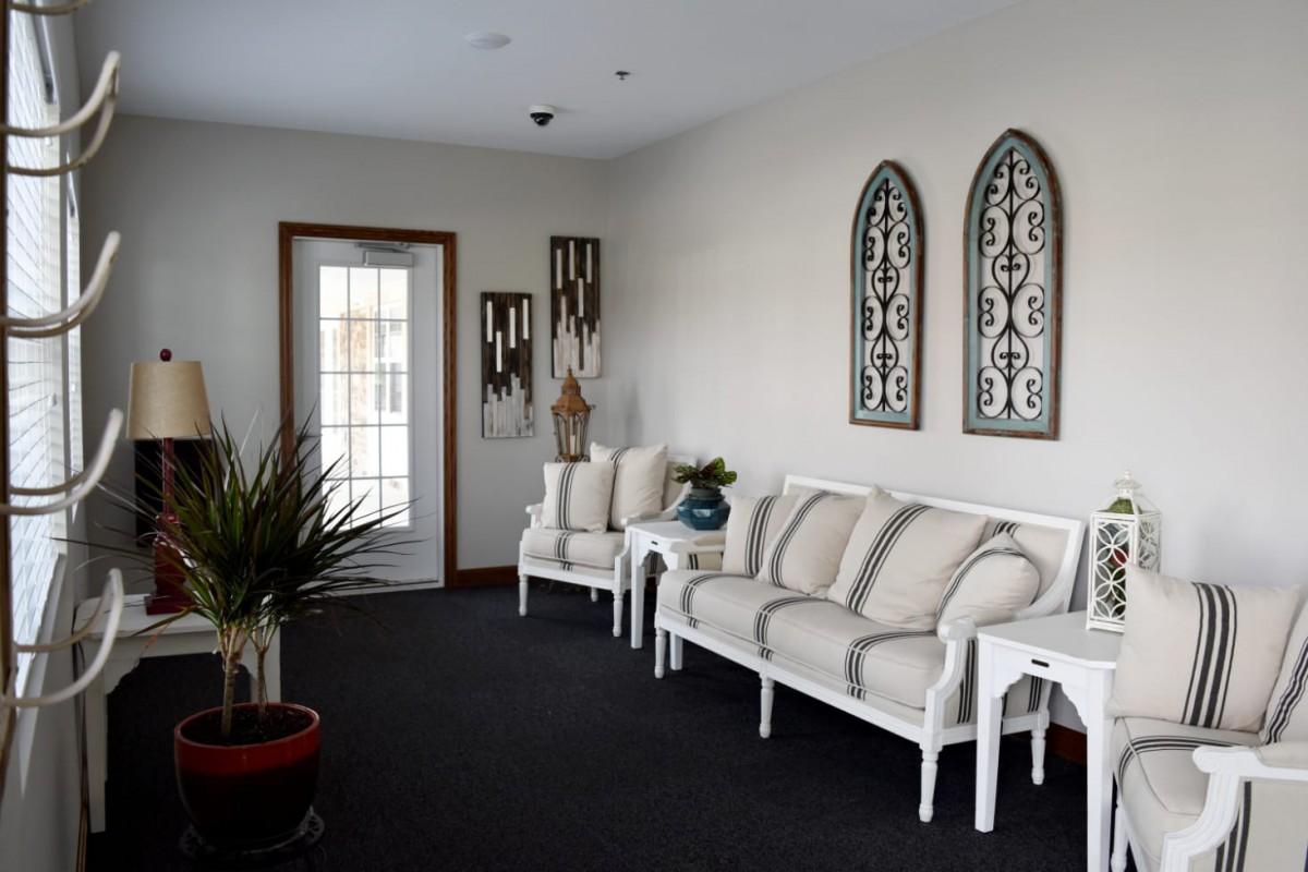 A cozy waiting room with white furniture and decorative wall art.