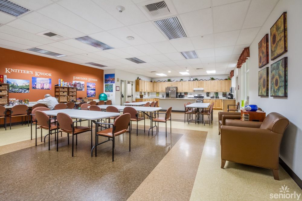 A community center interior with tables and chairs arranged near a kitchen area, ideal for meetings or gatherings.