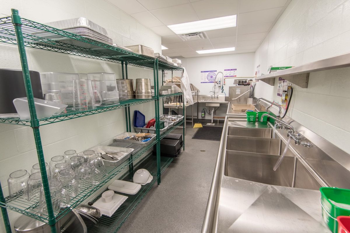 A well-organized commercial kitchen with stainless steel sinks and shelving.