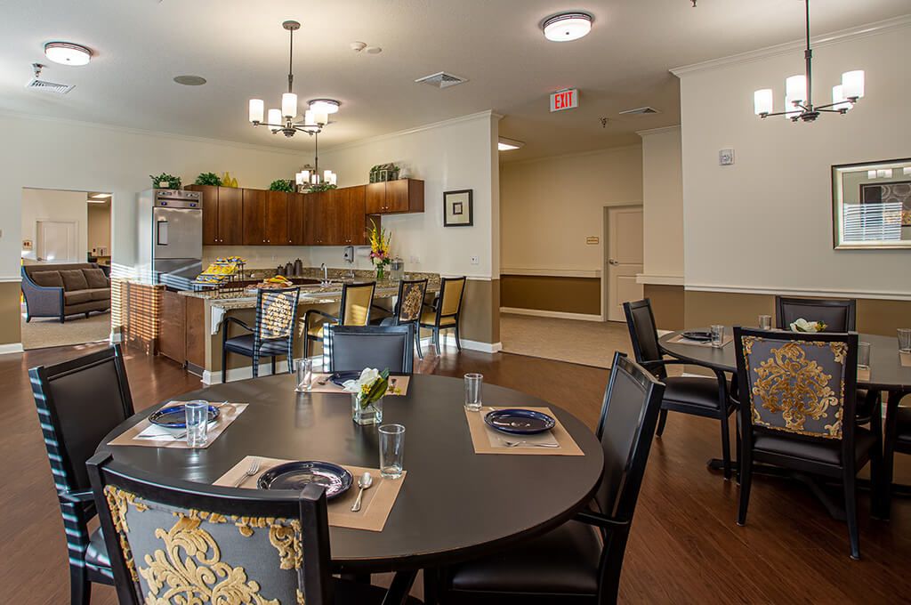 A well-arranged dining area with set tables and a view of a kitchen in the background.