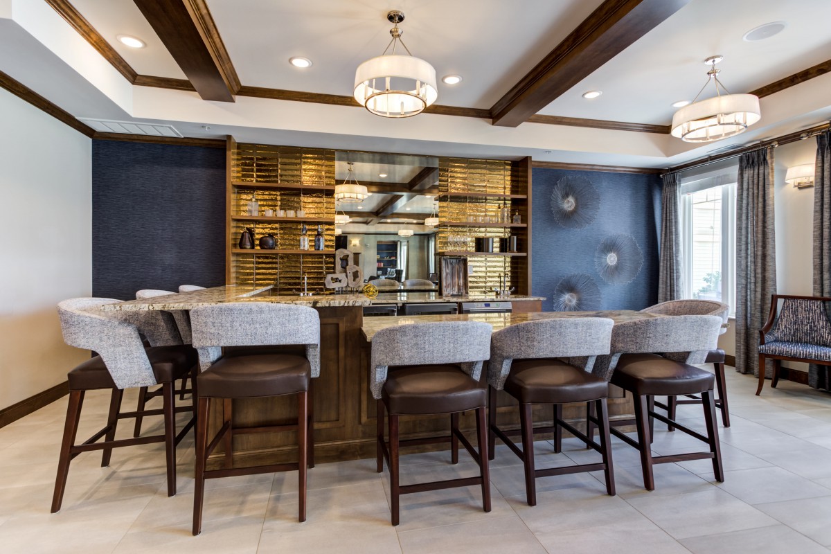A stylish home bar with modern decor and ample seating, featuring elegant lighting and a well-organized wine display.