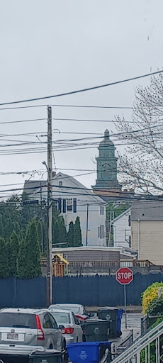 A view of a building with a prominent tower, surrounded by power lines and residential structures.
