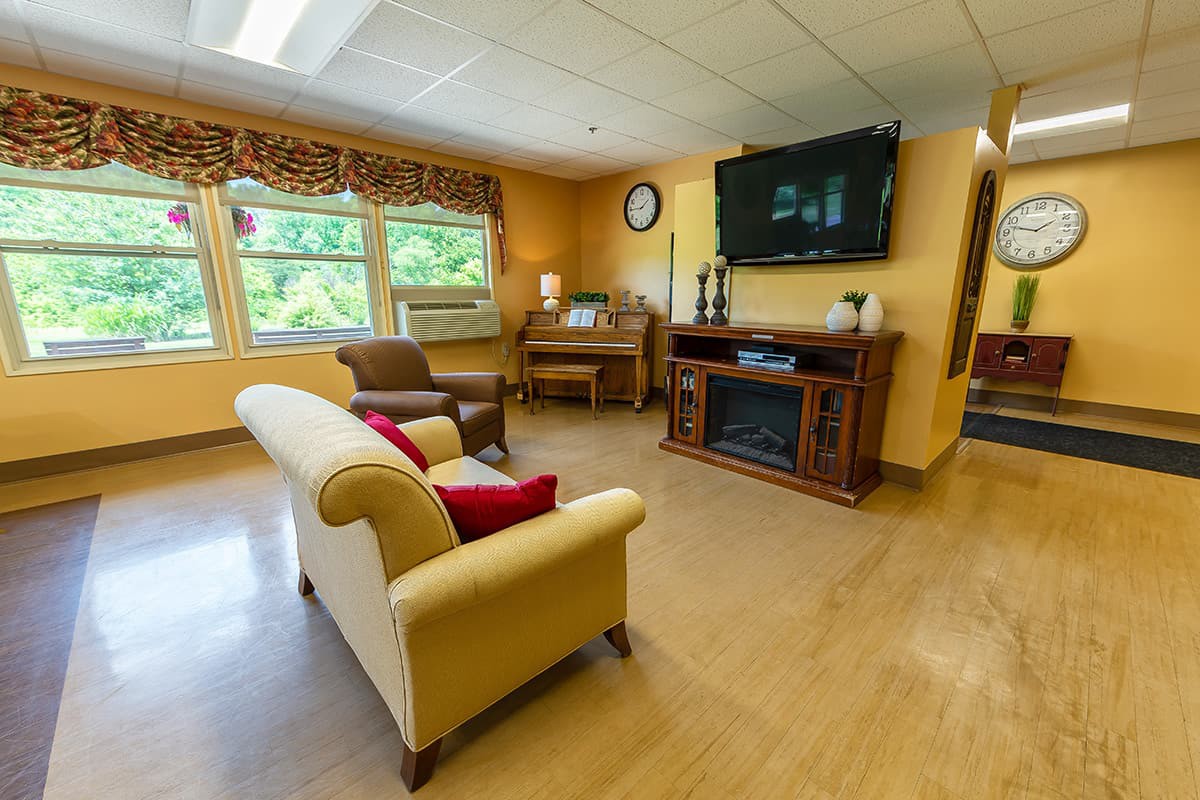 A cozy living room with a sofa, chairs, television, and large windows.