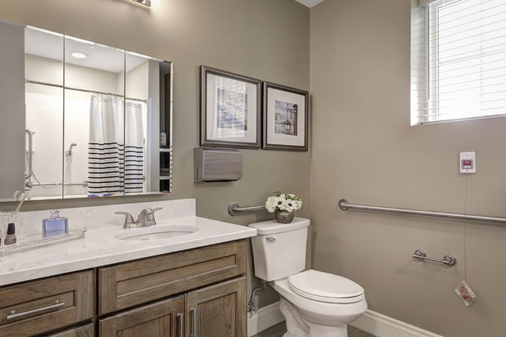 A modern bathroom with a wooden vanity, white countertop, and decorative wall art.