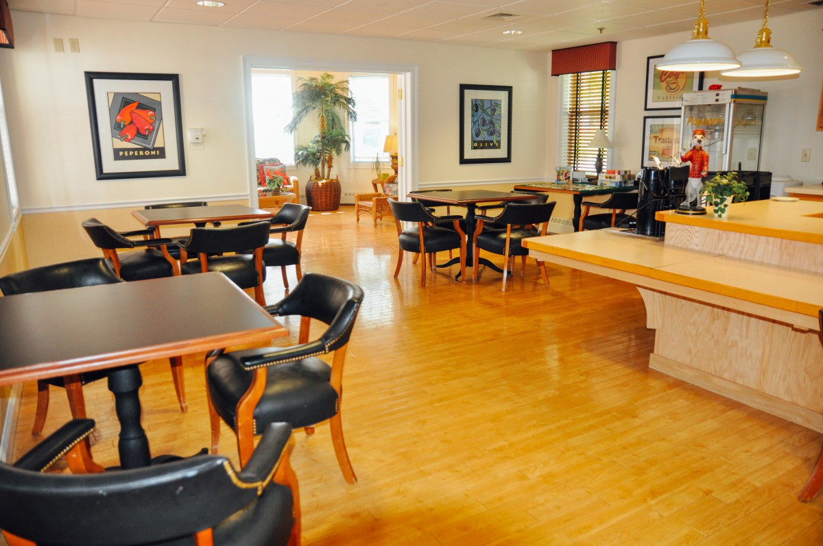 A cozy restaurant dining area with wooden floors, tables, and chairs.