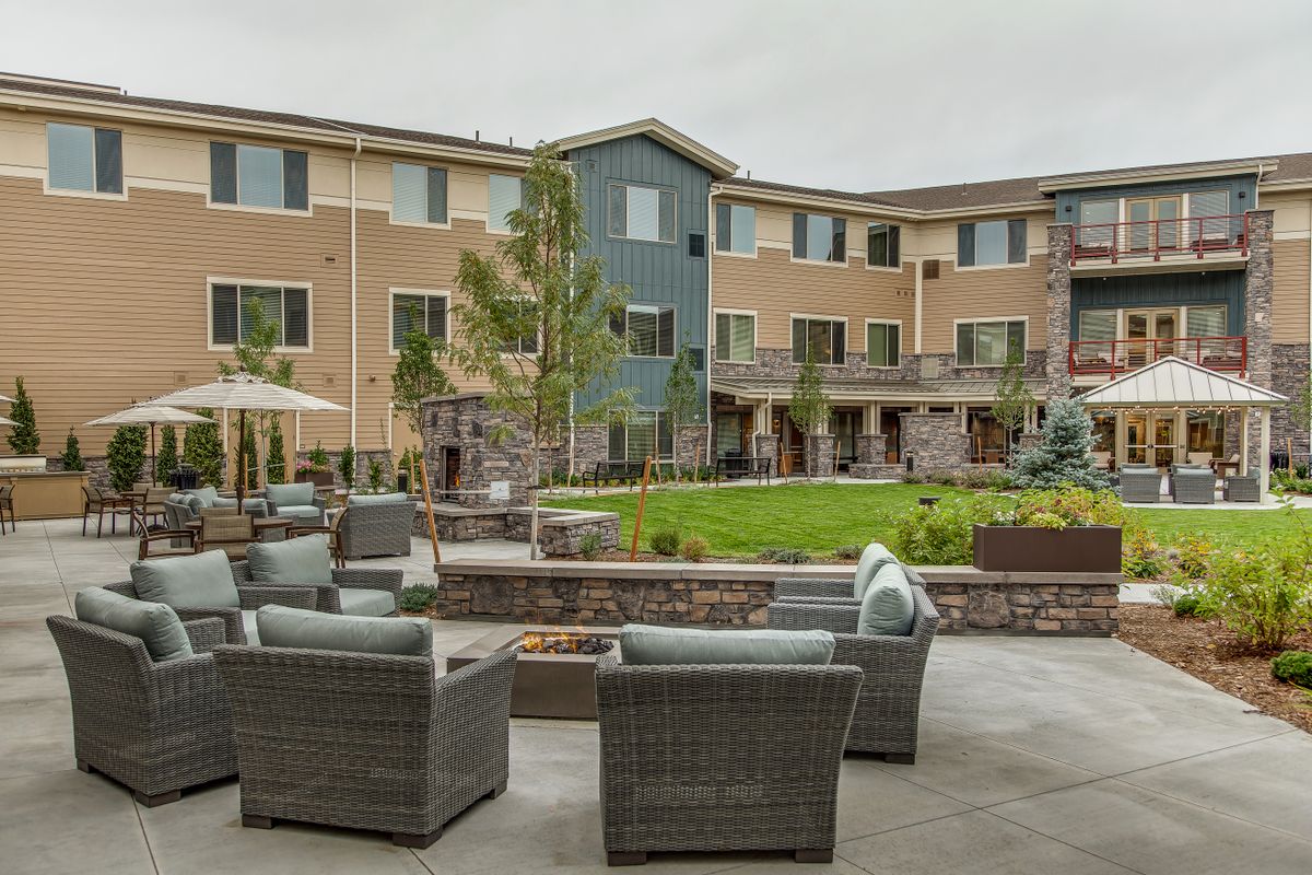 A modern apartment complex with outdoor seating and landscaped garden area.
