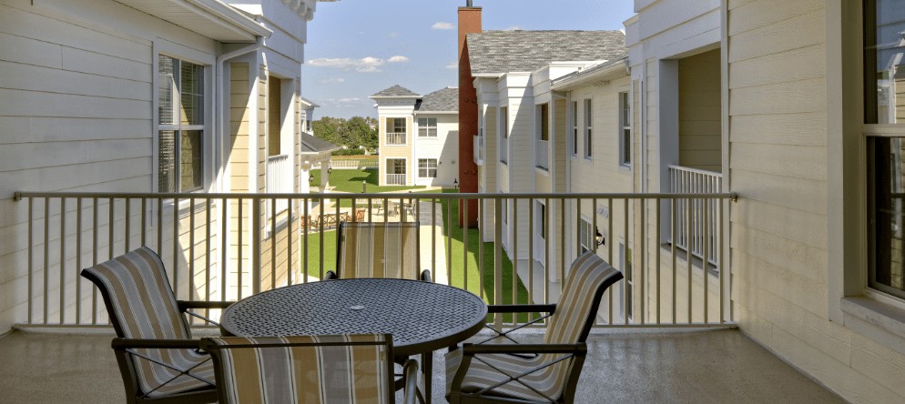 A view from a balcony featuring outdoor furniture and overlooking a residential apartment complex.