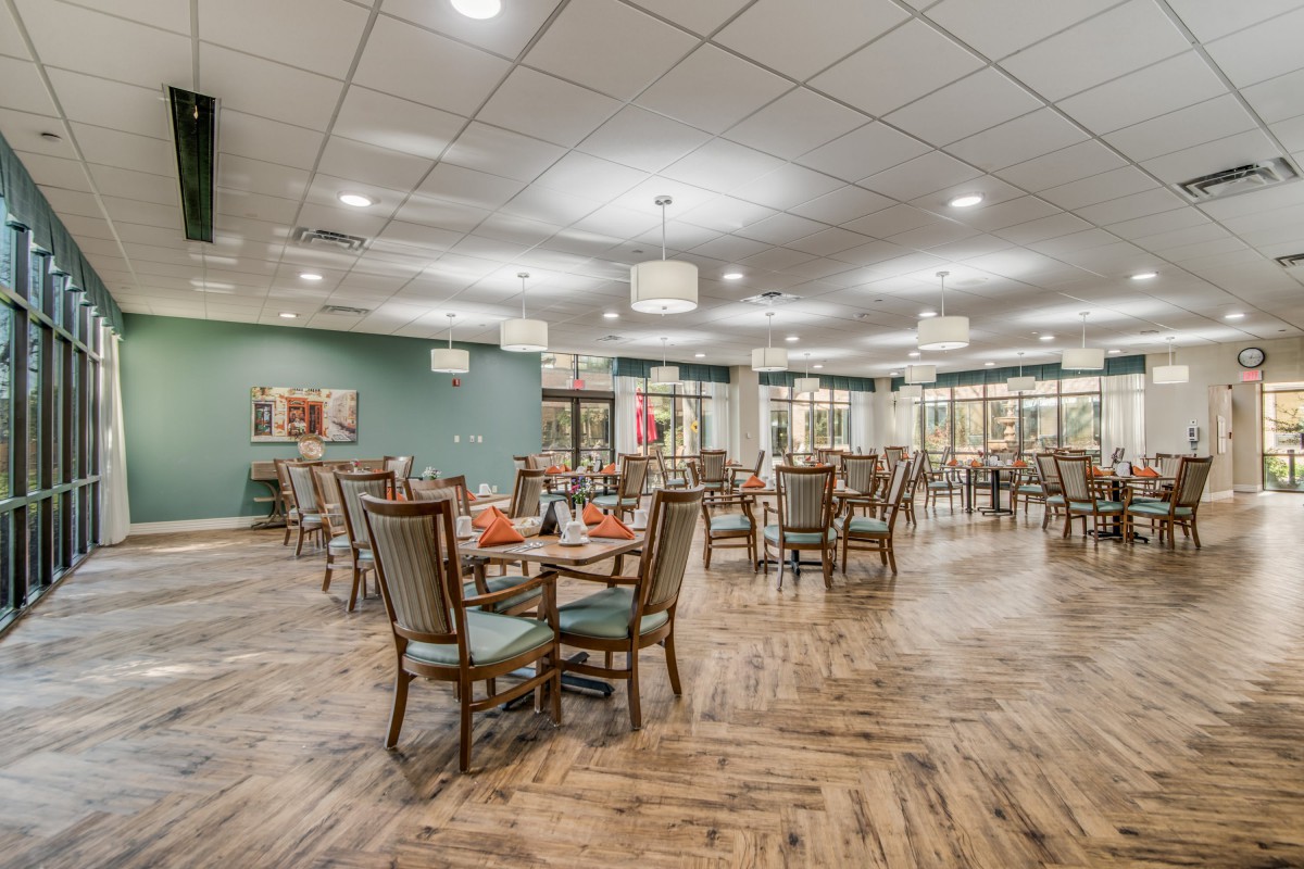 Spacious dining area with neatly arranged tables and chairs, featuring wooden flooring and elegant decor.