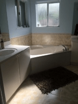 A modern bathroom interior featuring a bathtub, sink, and window.