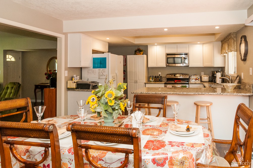 A cozy kitchen and dining area with a table set for a meal, featuring sunflowers as a centerpiece.