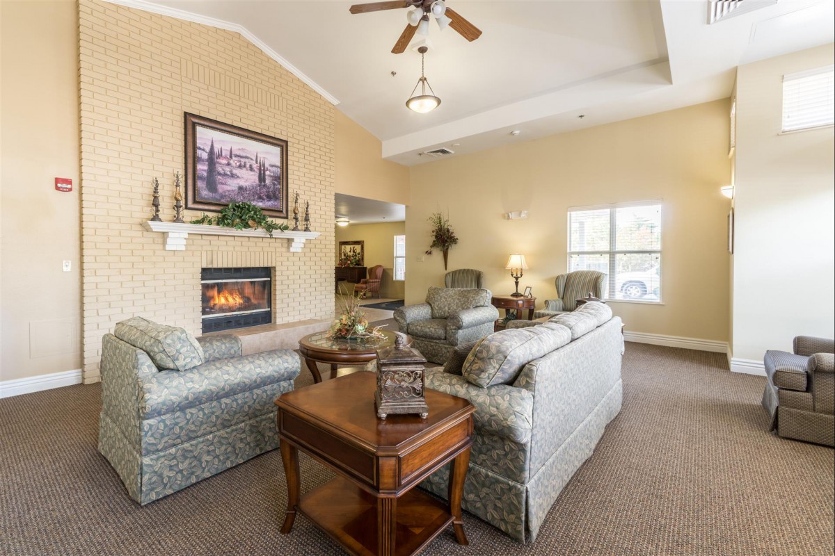 A cozy living room with a fireplace, sofas, and a ceiling fan.
