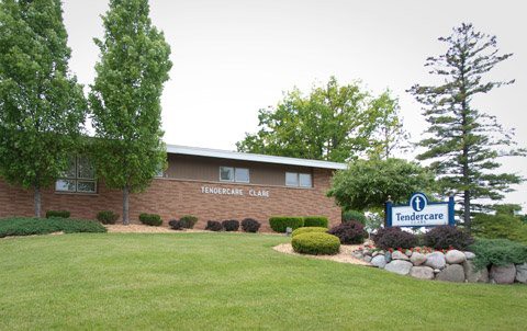A small brick office building with well-maintained landscaping and a sign in front.