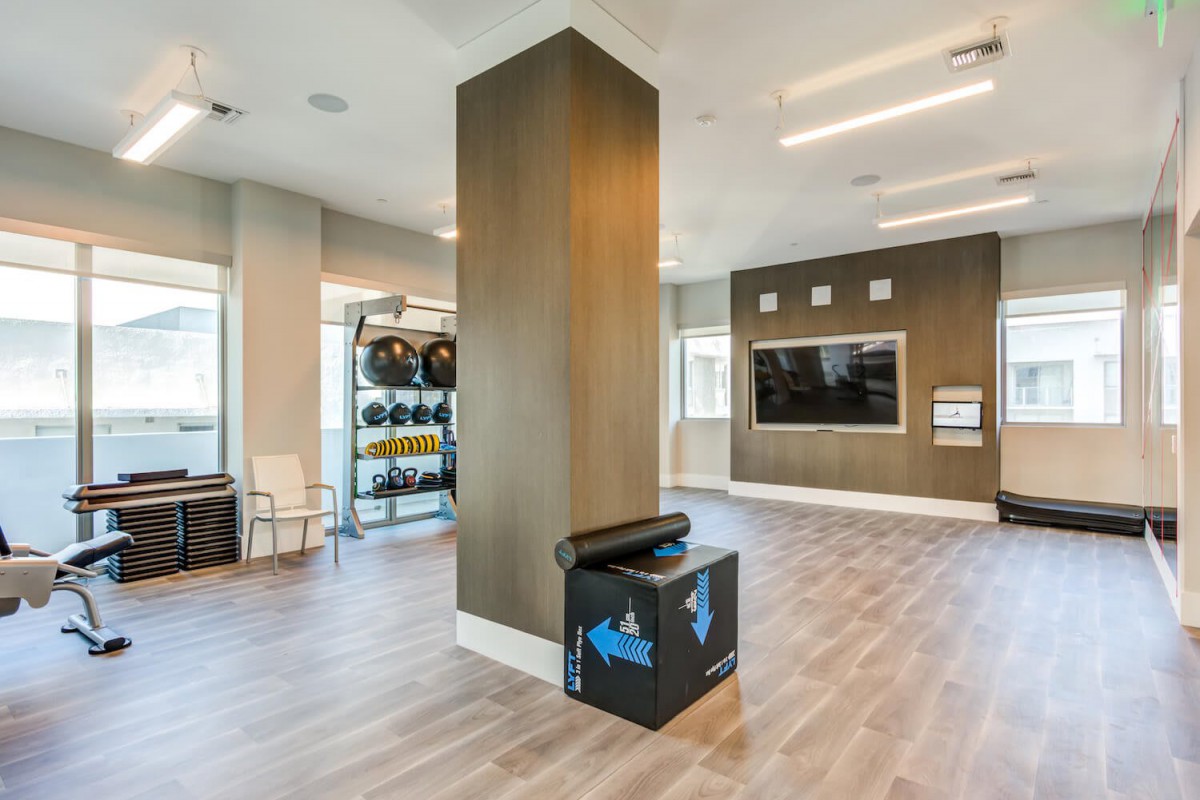 A modern fitness center with exercise equipment and a large TV screen.