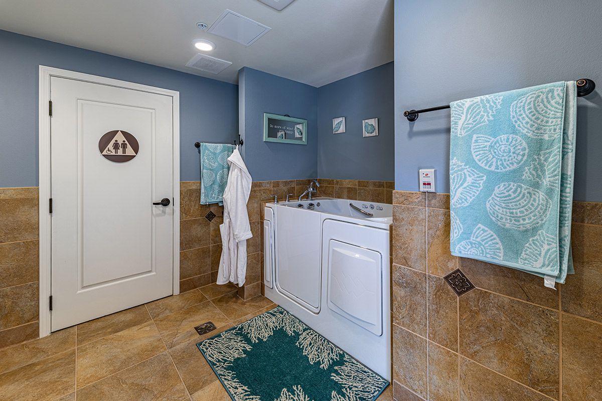 A cozy laundry room with a washing machine, dryer, and blue walls adorned with decorative towels and a bathrobe.