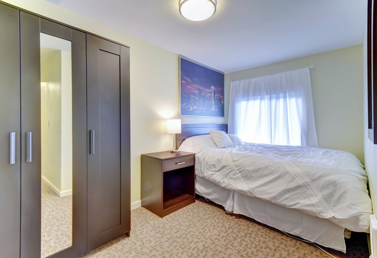 A cozy bedroom with a bed, bedside table, lamp, and wardrobe.