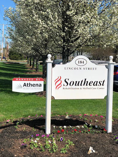 A visible sign displaying Athena and Southeast businesses located on Lincoln Street amidst blooming trees.