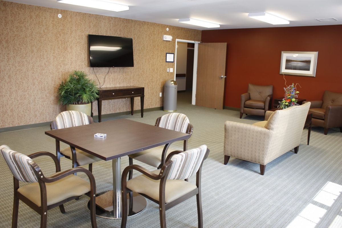 A comfortable waiting room with a seating area, table, television, and decor.