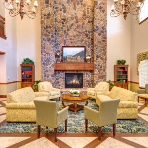 A cozy living room with a stone fireplace, elegant chandeliers, and comfortable seating arrangements.