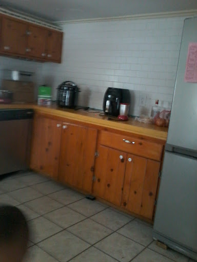 A view of a home kitchen featuring wooden cabinets and various kitchen appliances.