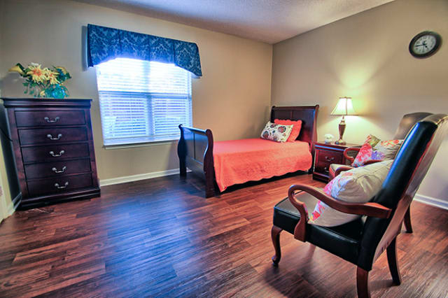 A cozy bedroom with a single bed, featuring hardwood flooring and traditional wooden furniture.