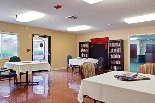A spacious community room featuring tables and chairs, complemented by bookshelves filled with books.