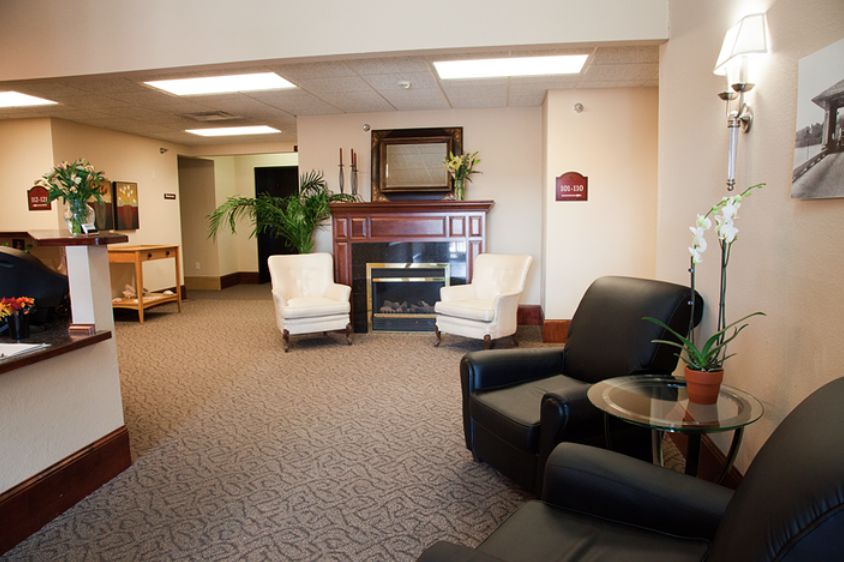 A cozy lobby with a seating area featuring armchairs and a fireplace beneath a mounted television.