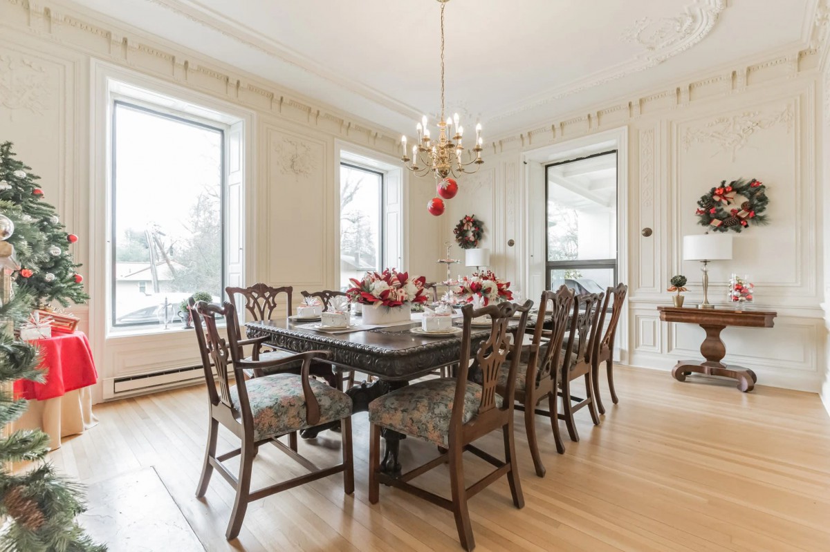 A beautifully decorated dining room with a chandelier and large windows letting in natural light.