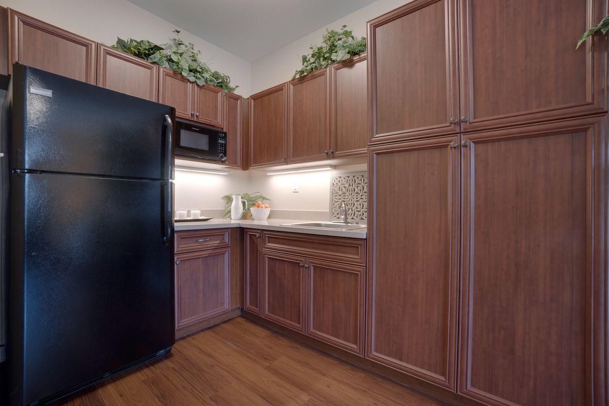 A modern kitchen with wooden cabinets, a black refrigerator, and a microwave.