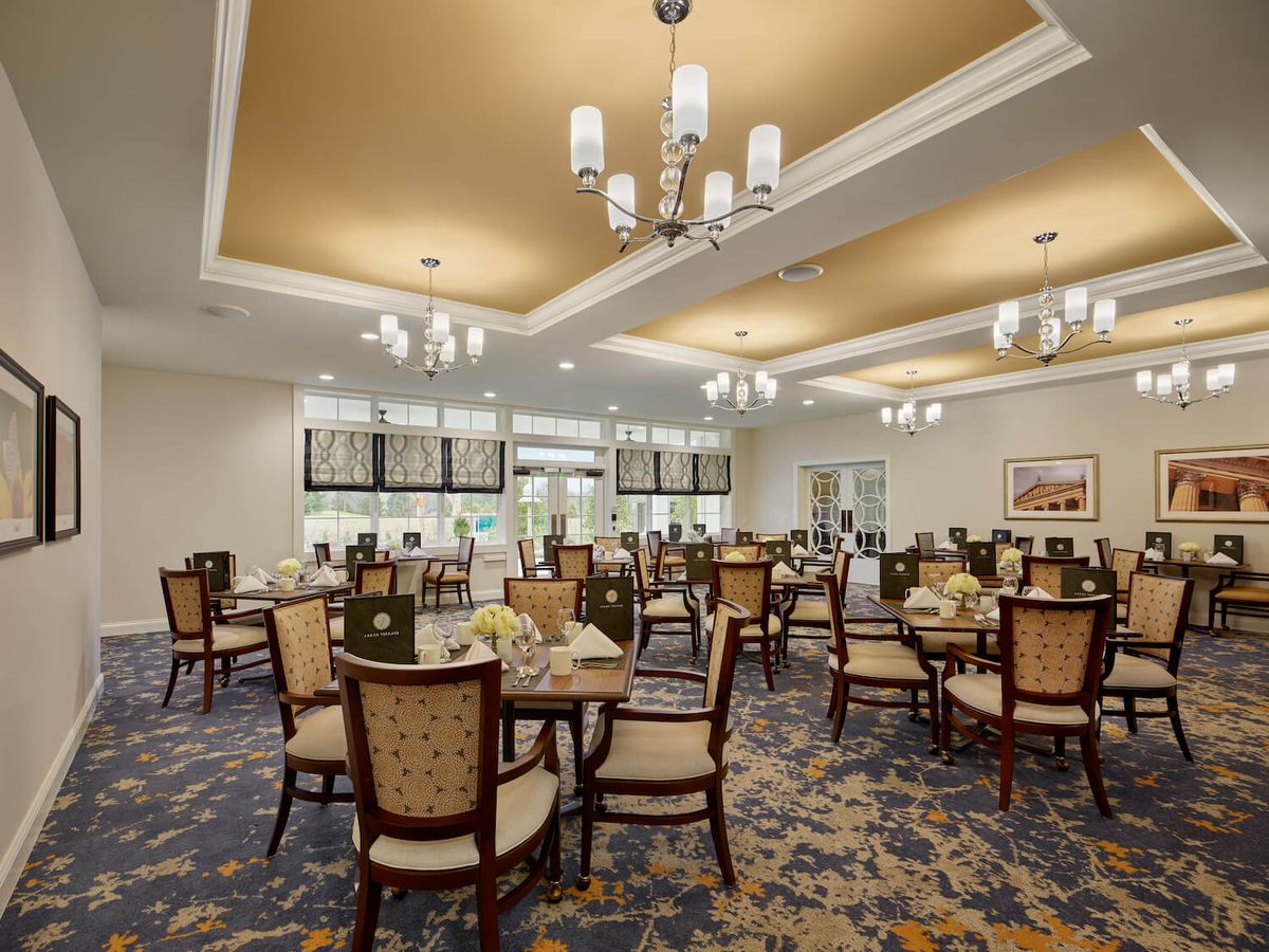 An elegantly designed dining room with chandeliers and neatly arranged tables and chairs.