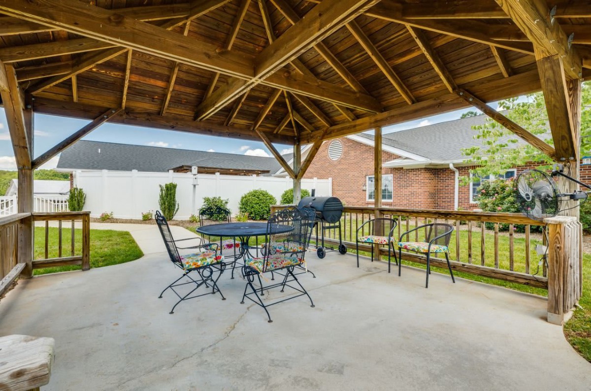 Covered patio area with a gazebo, outdoor seating, and a grill in the backyard.