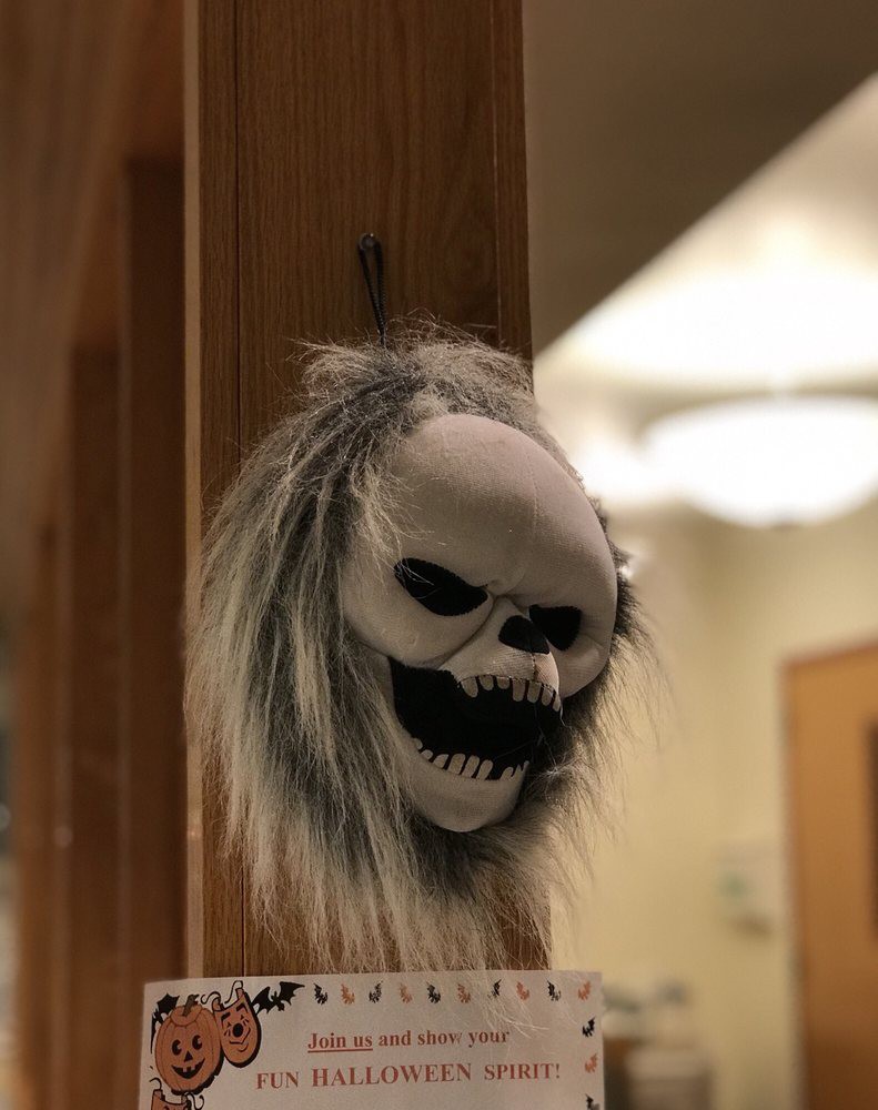 A spooky skull mask with long hair hanging as a Halloween decoration.