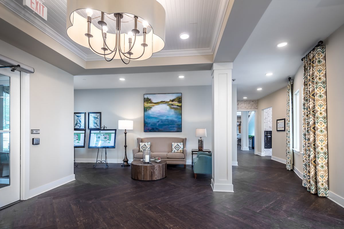 A modern lobby with stylish decor, featuring a chandelier, artwork, and a comfortable seating area.