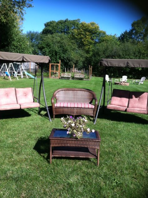 Outdoor garden seating area with swings and wicker furniture.