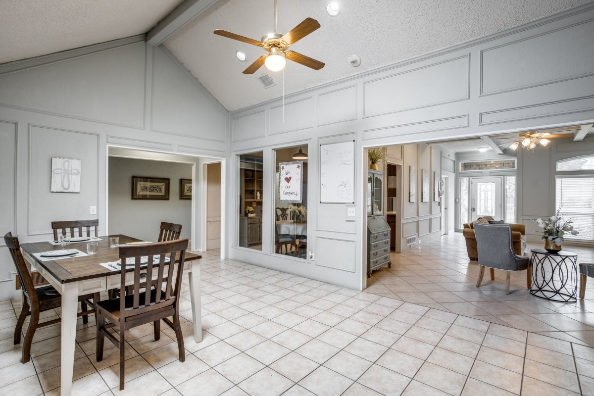 A spacious kitchen and dining area with a ceiling fan and tiled flooring.