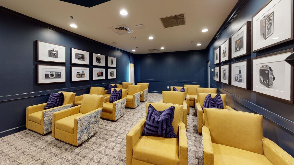 A modern lounge with yellow armchairs and decorative pillows, adorned with framed photos on the walls.