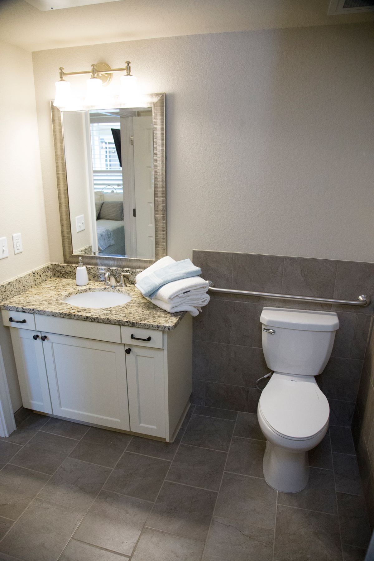 A clean and modern bathroom featuring a sink, toilet, and mirror with neatly folded towels on the counter.