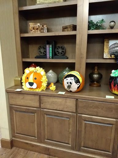 A collection of creatively decorated pumpkins on a shelf, featuring a lion and a cartoon character.
