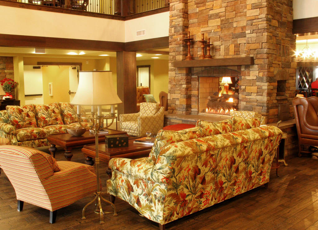 A cozy living room with a rustic fireplace and floral sofas.
