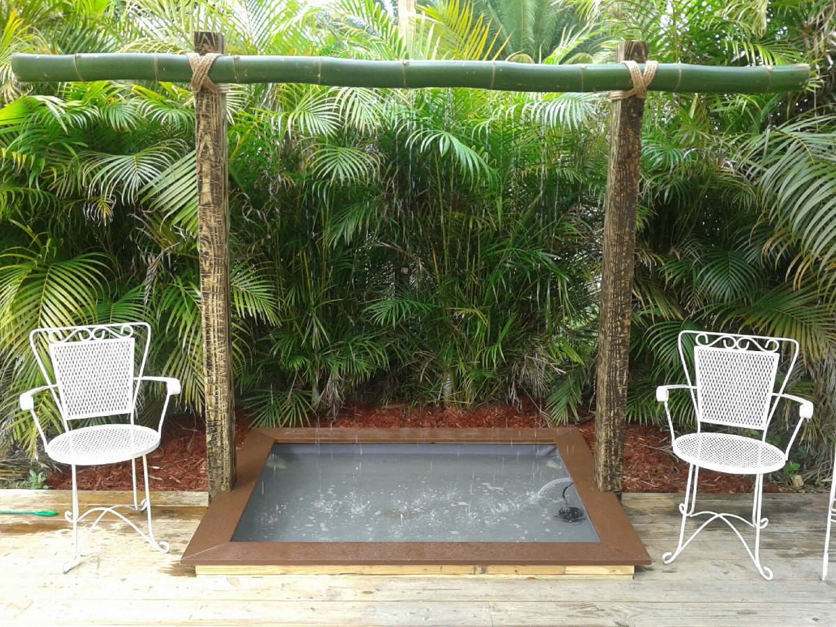 Outdoor hot tub with surrounding tropical plants and bamboo frame.